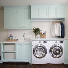 a washer and dryer in a laundry room with green cabinets, white counter tops and wood flooring