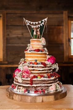 a multi layer cake decorated with flowers and an animal topper on a wooden table