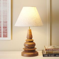 a lamp sitting on top of a table next to a stack of books and a book