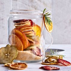 a glass jar filled with dried fruit and sliced oranges on top of a table