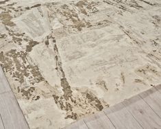 a beige and brown area rug sitting on top of a wooden floor