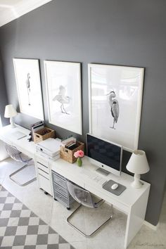 a desk with two pictures on the wall above it