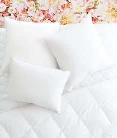 two white pillows sitting on top of a bed in front of a floral headboard