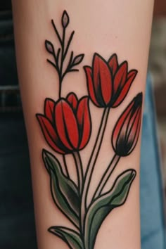 a close up of a person's arm with tattoos on it and red flowers