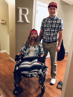 a man standing next to a woman in a wheel chair on a hard wood floor