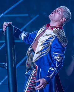 a man in a blue and gold outfit standing next to a metal pole with his eyes closed