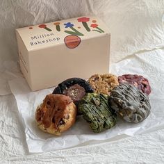 an assortment of pastries sitting in front of a box on top of a bed