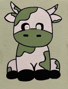 a green and white cow sitting on the ground