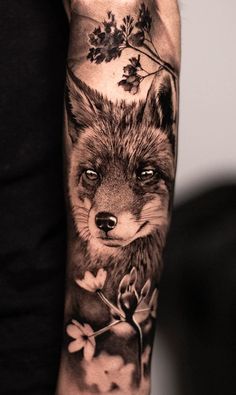 a man's arm with a fox and flowers tattoo design on it, in black and white