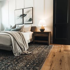 a bed sitting on top of a wooden floor next to a night stand and lamp