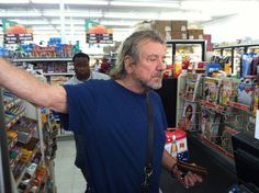 a man is standing in the aisle of a grocery store with his arm extended out