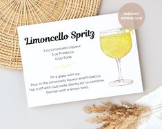 a card with a glass of lemonade on it next to a straw hat and flowers