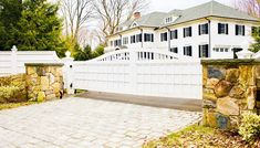 a large white house behind a stone fence