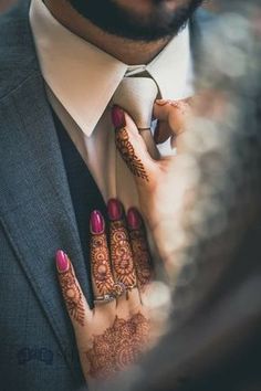 a man in a suit and tie with his hands on his chest, wearing henna