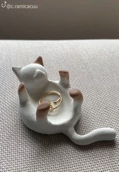 a white ceramic cat with a ring on it's back