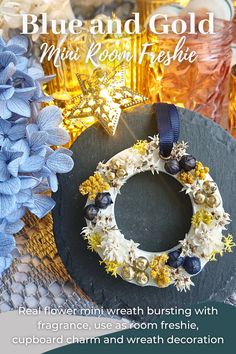 a blue and gold wreath on top of a black plate with flowers in the background