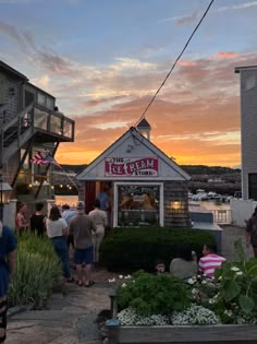 people are standing outside at the ice cream shop in front of an oceanfront building