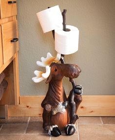 a wooden moose holding a roll of toilet paper on its back and sitting next to it