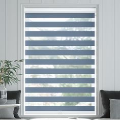 a living room with a large window covered in shades of grey and white stripes on the blinds