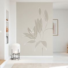 a living room with white walls and flowers on the wall, in front of a book shelf