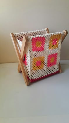 a crocheted basket sitting on top of a wooden easel with two handles