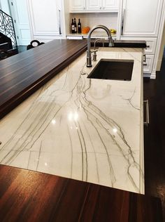 a marble kitchen counter top with an island style sink and faucet in the middle