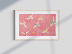 a painting with birds flying in the air on a pink wall above a white frame