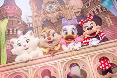 several stuffed animals are sitting on top of a wall in front of a disney castle