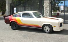 a white car with red, yellow and orange stripes parked in front of a gate