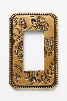 an ornate light switch plate cover with flowers and leaves painted on the front in gold