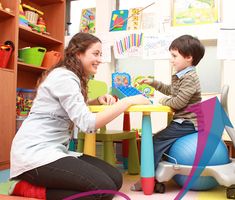 a woman playing with a child on an exercise ball in a room full of children's toys