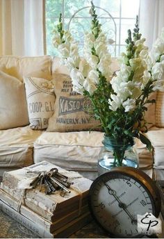 a vase filled with white flowers sitting on top of a table next to an alarm clock