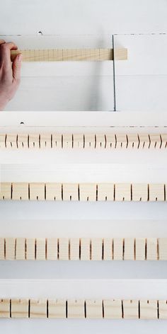 a person holding a ruler in front of some wooden planks that are lined up on the wall