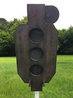 a traffic light sitting in the middle of a grass covered field with trees in the background