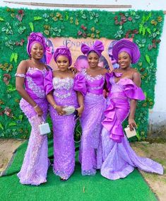 three women in purple dresses standing next to each other on a green carpeted area