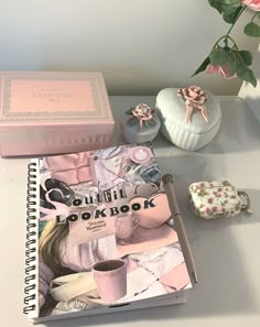 a pink book sitting on top of a white table next to a vase with flowers