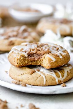 two cookies with icing on top are sitting on a plate next to another cookie