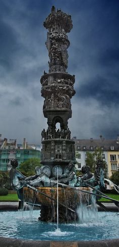 a water fountain with statues on it in the middle of a park