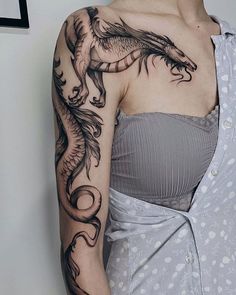 a woman with a dragon tattoo on her arm and shoulder, wearing a gray dress