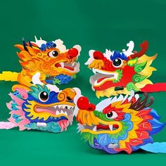 three brightly colored dragon heads on green background with red, yellow, and blue decorations