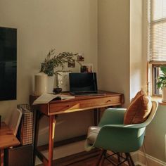 a desk with a laptop computer on top of it next to a chair and potted plant