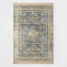 a blue and beige rug with fringes on the bottom, in front of a white wall