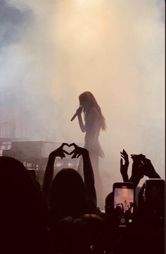 a woman standing on top of a stage with her hands in the air while holding a microphone