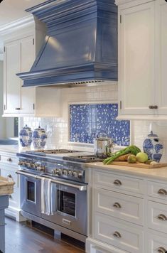 a kitchen with blue and white tiles on the backsplash, stove top oven and cabinets