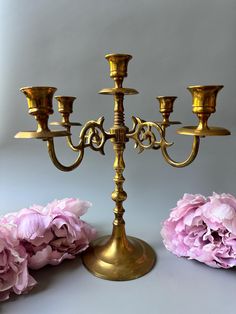 a gold candelabra with five candles and pink flowers