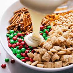 a white bowl filled with cereal and candy corn flakes being poured into the bowl