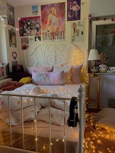 a bed with lots of pillows and lights on the headboard in a small room