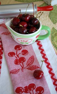 cherries are in a small bowl on a table with red and white placemats