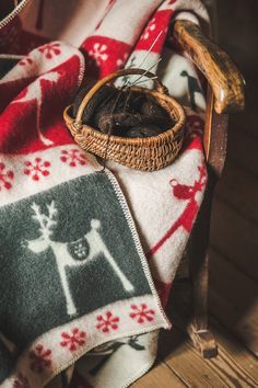 a basket with some knitting needles in it sitting on a blanket next to a pair of scissors