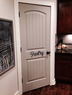 a white door with the word pantry painted on it's side in a kitchen